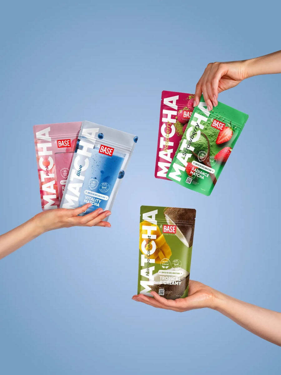Hands holding The Base flavoured matcha pouches against a blue background