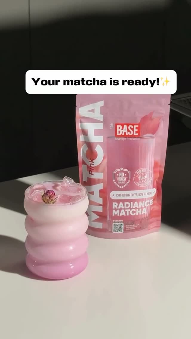 Pink matcha drink in a ribbed glass next to The Base Radiance Matcha pouch